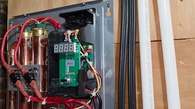 Open electric tankless water heater showing the control board, heating chambers and wiring during a repair